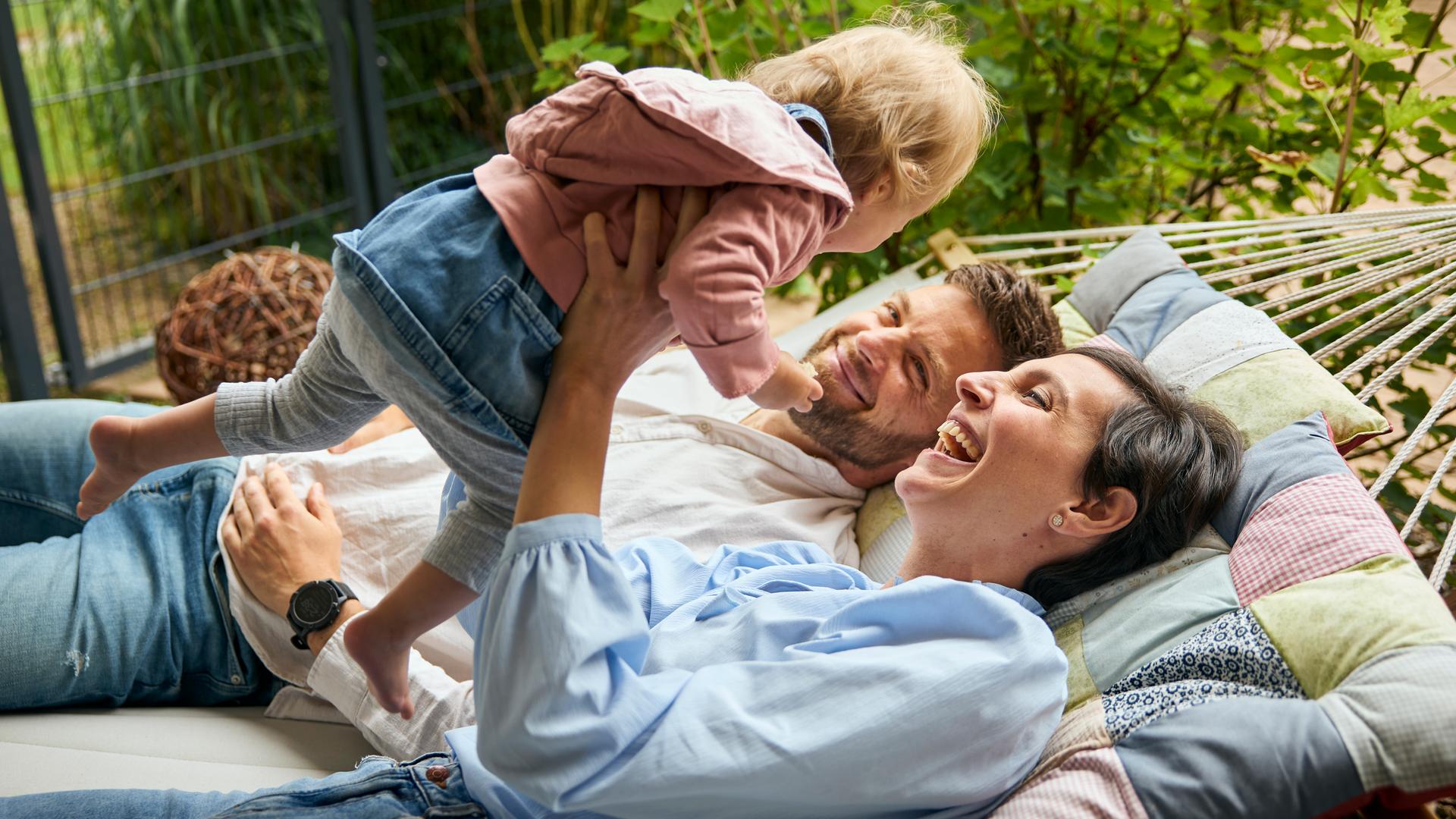Nicolina und Martin liegen mit der einjährigen Adoptivtochter in der Hängematte.