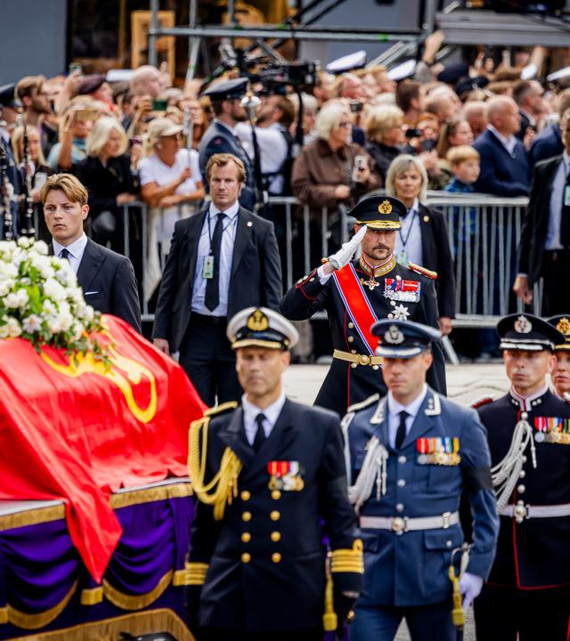 Beerdigung von König Harald von Norwegen in Oslo. Der Sarg mit einem roten durch wird von Männern in Uniform getragen.