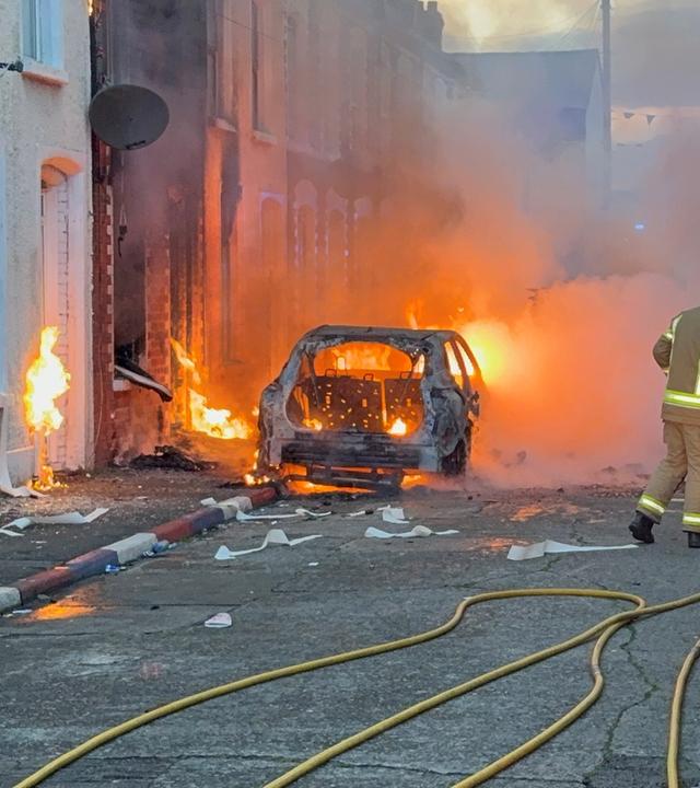 Eine Familie wird in ein Fahrzeug der PSNI gebracht, nachdem sie aus Häusern gerettet wurde, die in der Lendrick Street im Osten von Belfast in Brand geraten waren. Die Unruhen waren als Reaktion auf den Messerangriff am Montagabend in der Stadt ausgebrochen.