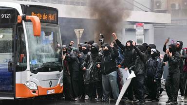 Demonstranten suchen am 9. Oktober 2026 während einer von Gewerkschaften organisierten Demonstration gegen die Haushaltsmaßnahmen der Bundesregierung in der Nähe des Bahnhofs Brüssel-Süd Schutz hinter einem Bus.