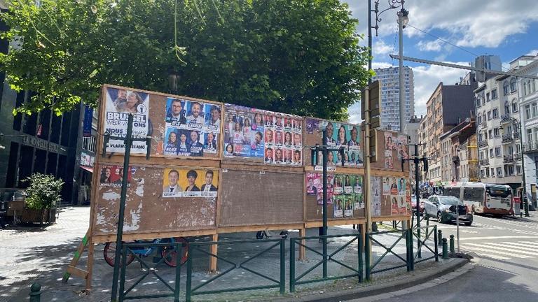 Auf einer Plakatwand in Belgien sind Wahlplakate verschiedener Kandidatinnen und Kandidaten zu sehen.