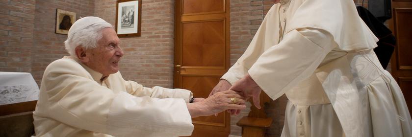 Papst Benedikt XVI. und Papst Franziskus reichen sich die Hände im Vatikan.