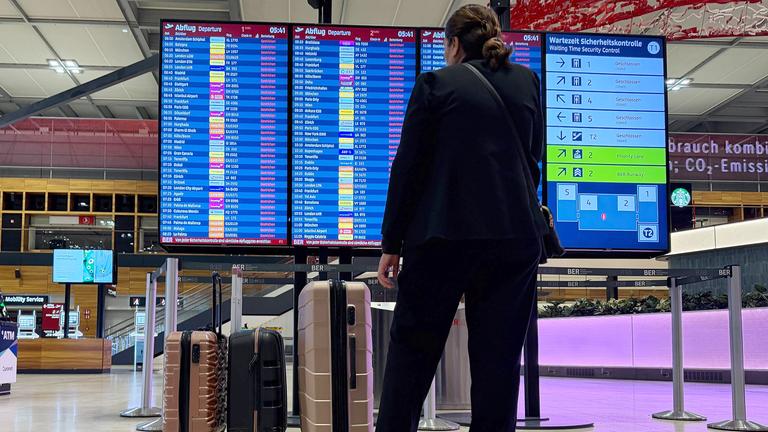 Ein Mann steht in der Halle des Flughafens BER an einer Informationstafel, die alles Flüge als gestrichen anzeigt, aufgenommen am 18.03.2026