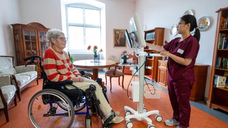 Rheinland-Pfalz, Trier: Pflegefachkraft ruft in einer gestellten Szene im Altenwohn- und Pflegeheim der Vereinigten Hospitien in Trier das Krankenblatt von Heimbewohnerin auf dem Teledoc-Rollständer auf.