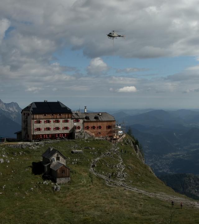 Das Watzmannhaus im Umbau, ein Helikopter fliegt über der Berghütte.