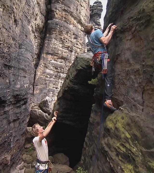 Bergsteiger klettern an Felsen im Erbsandsteingebirge.