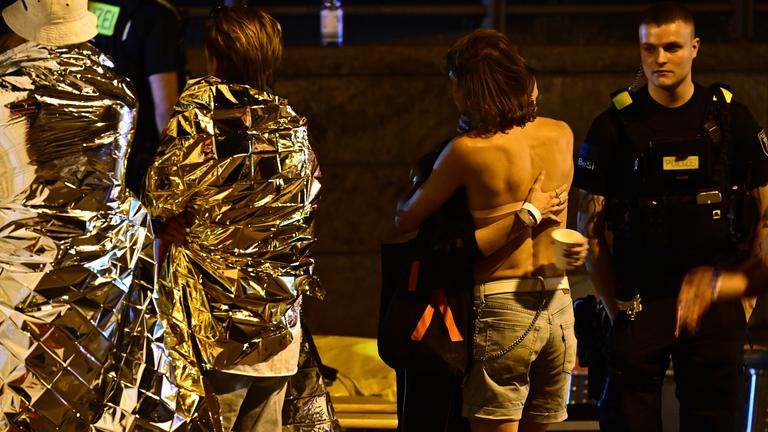In Rettungsdecken gehüllte Personen stehen neben einem Zelt der Feuerwehr nach dem Abbruch des Christopher Street Day (CSD) in Berlin.