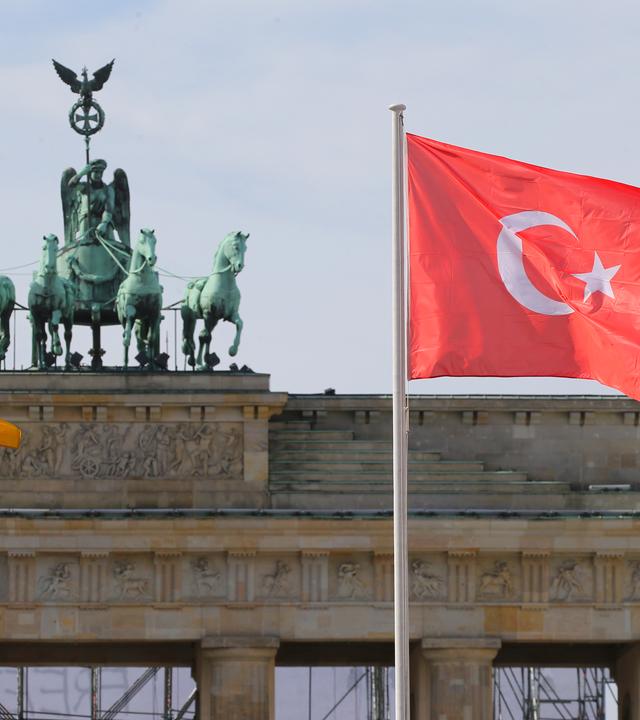 Die Deutsche und die Tuerkische Nationalflagge wehen vor dem Brandenburger Tor in Berlin