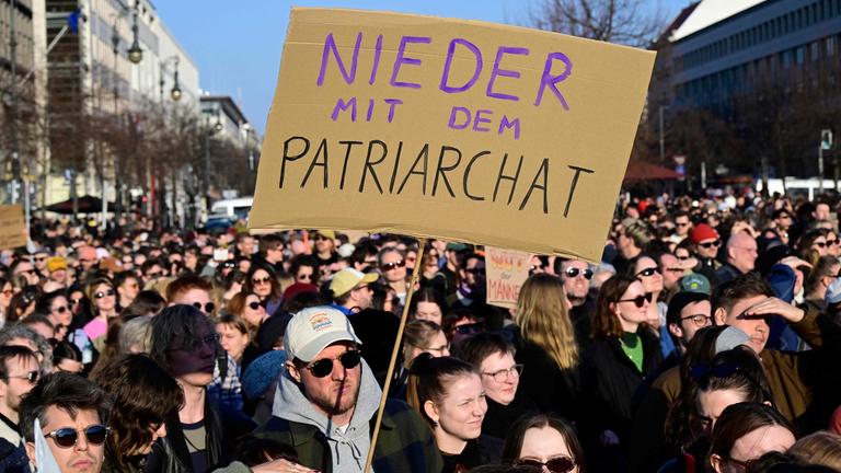 Demonstranten halten ein Plakat mit der Aufschrift „Nieder mit dem Patriarchat“ hoch.