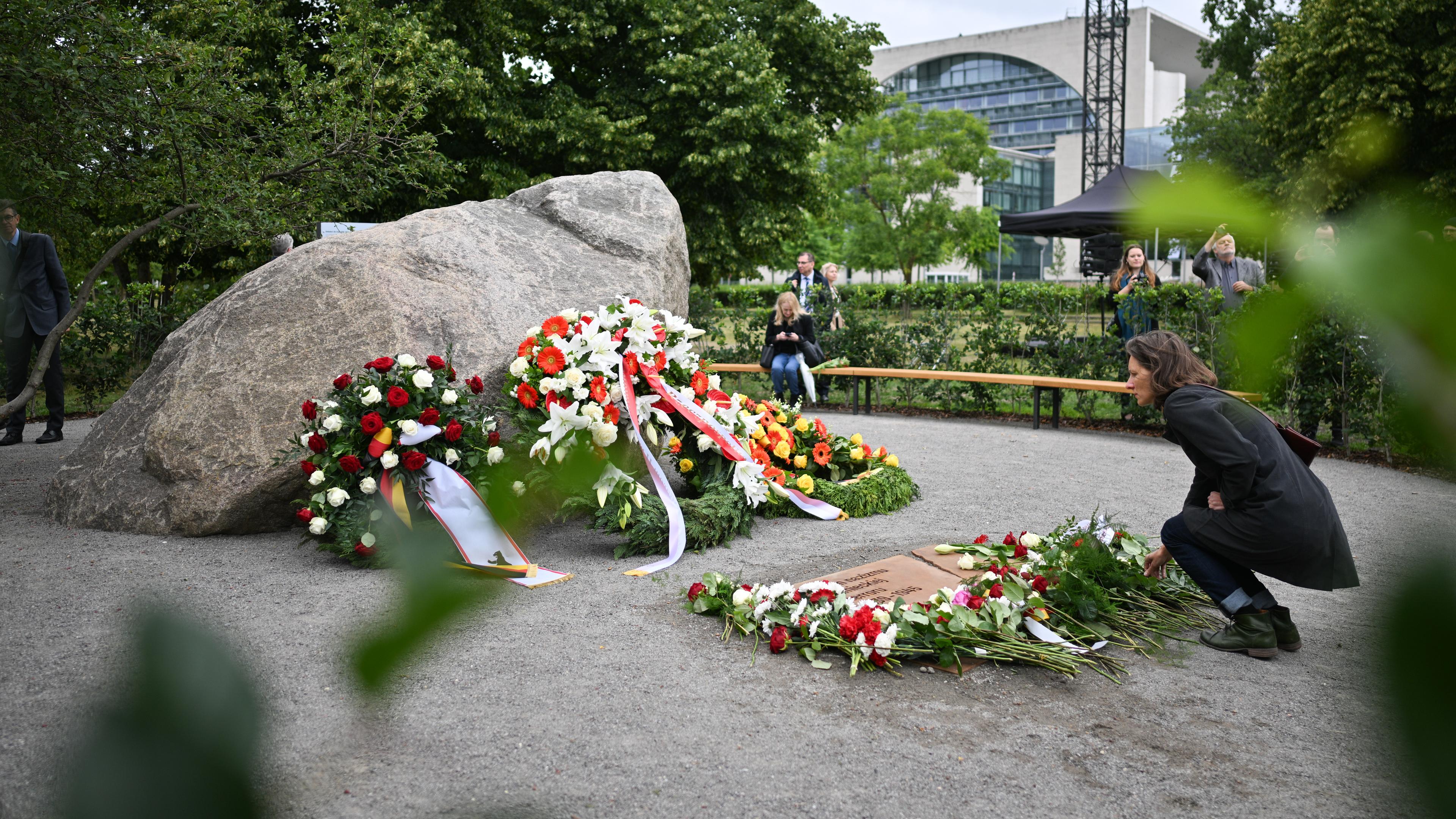  Eine Frau legt während der Übergabe eines temporären Denkmals zur Erinnerung an die polnischen Opfer des Zweiten Weltkriegs und der deutschen Gewaltherrschaft eine Blume ab.