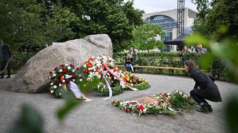  Eine Frau legt während der Übergabe eines temporären Denkmals zur Erinnerung an die polnischen Opfer des Zweiten Weltkriegs und der deutschen Gewaltherrschaft eine Blume ab.