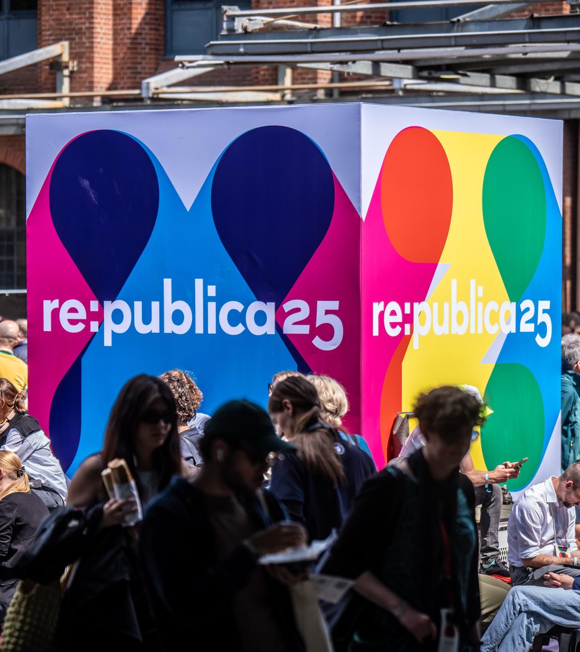 Besucher der Medienkonferenz Re:publica sitzen an einem Logo-Aufsteller am Veranstaltungsort «Station Berlin»