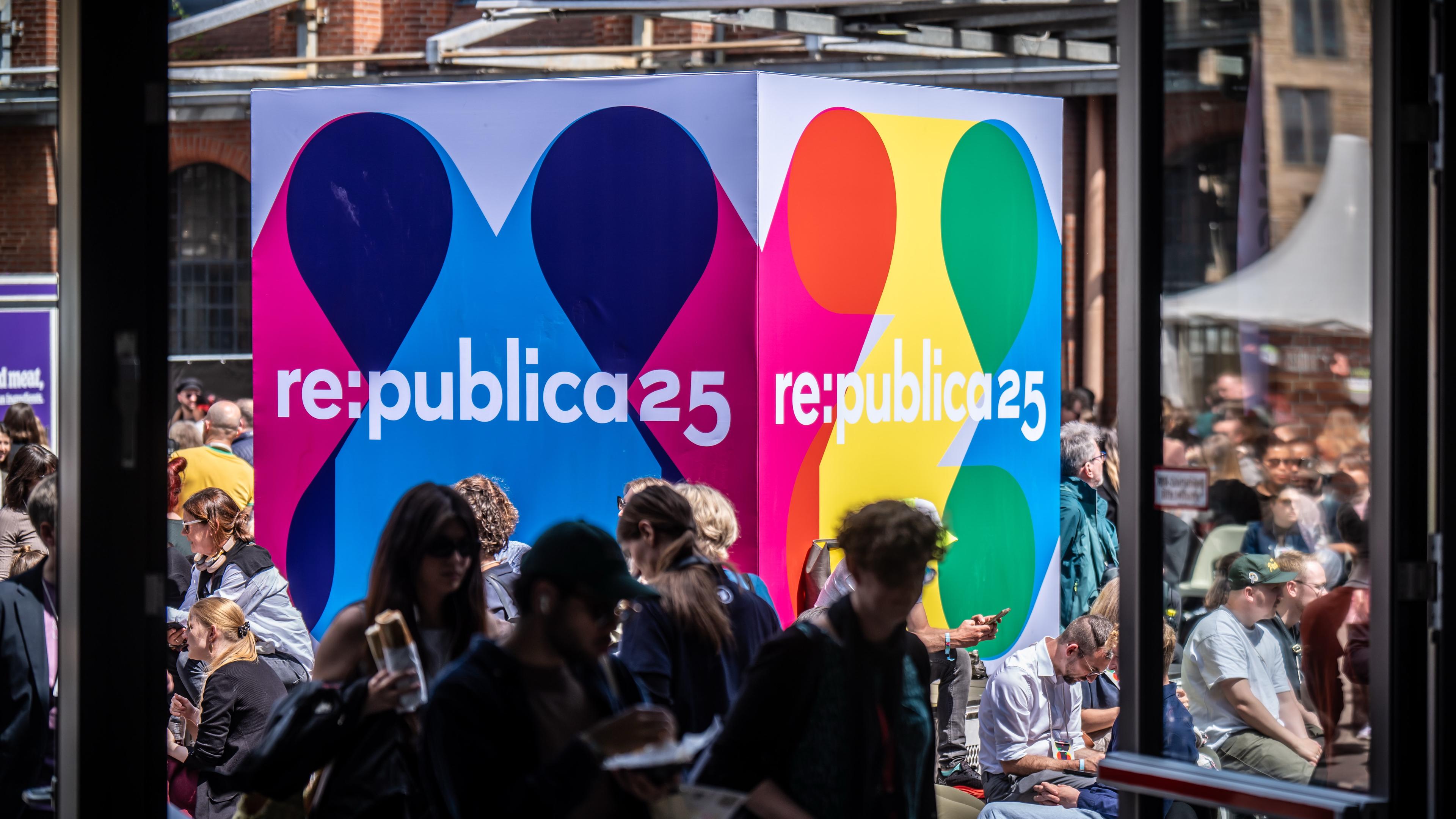 Besucher der Medienkonferenz Re:publica sitzen an einem Logo-Aufsteller am Veranstaltungsort «Station Berlin»