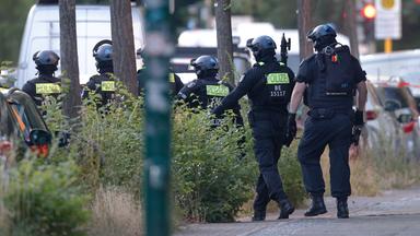 Polizisten sichern in Berlin-Marienfelde die Umgebung des Supermarktes, in dem ein Mann eine Frau als Geisel hält.