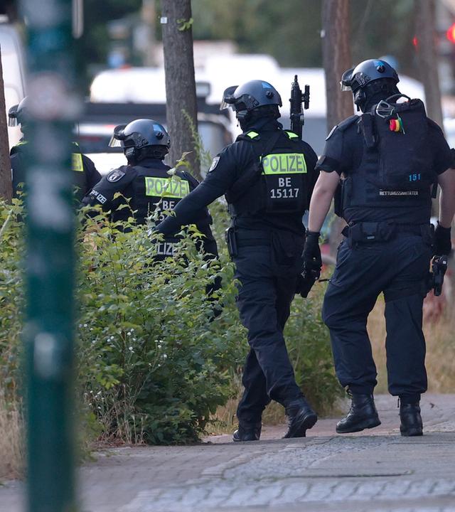 Polizisten sichern in Berlin-Marienfelde die Umgebung des Supermarktes, in dem ein Mann eine Frau als Geisel hält.