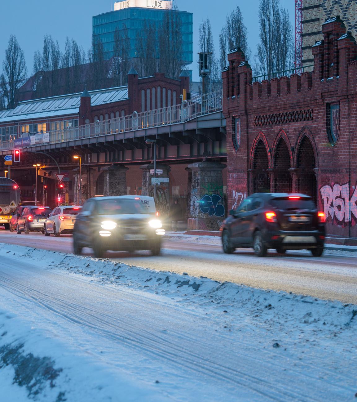 Zahlreiche Autos fahren in den frühen Morgenstunden über die verschneite Oberbaumbrücke.