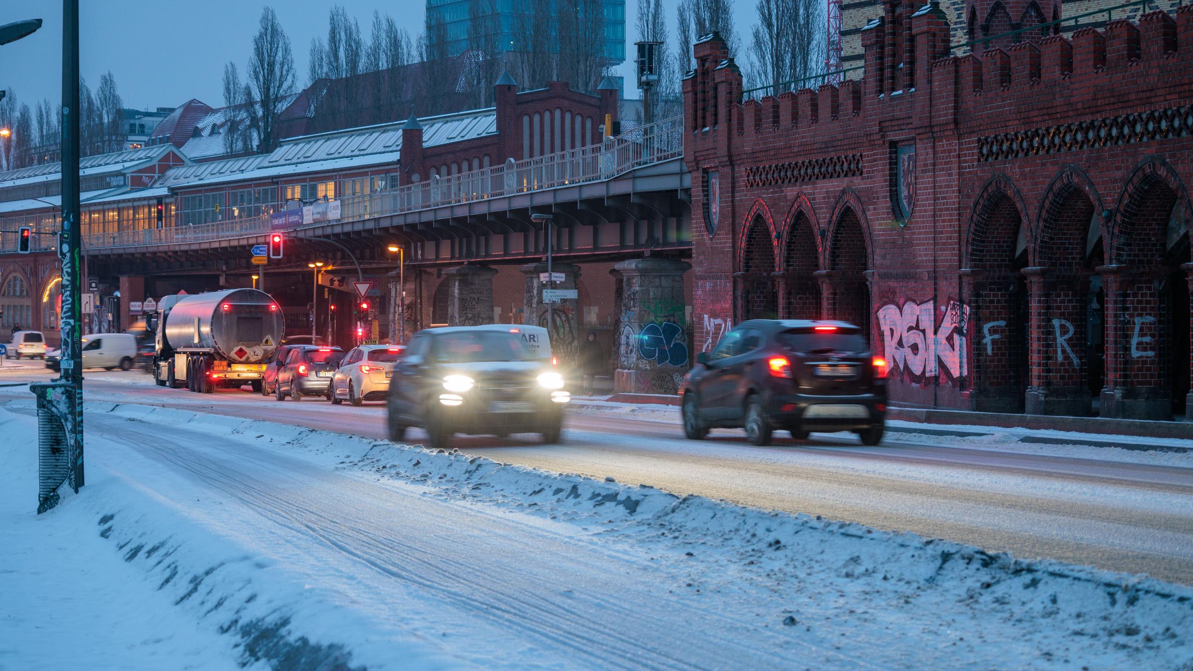 Zahlreiche Autos fahren in den frühen Morgenstunden über die verschneite Oberbaumbrücke.