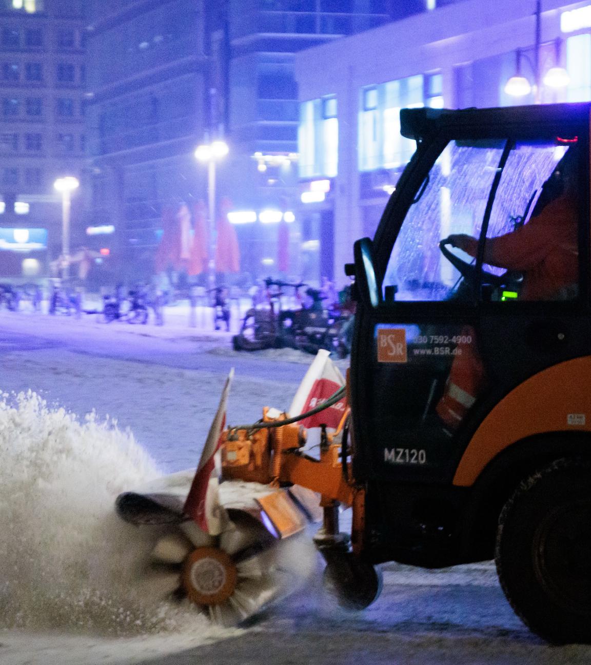Ein Schneeräumfahrzeug der BSR bürstet den Schnee vom vereisten Boden am Alexanderplatz