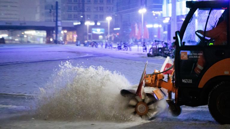 Ein Schneeräumfahrzeug der BSR bürstet den Schnee vom vereisten Boden am Alexanderplatz