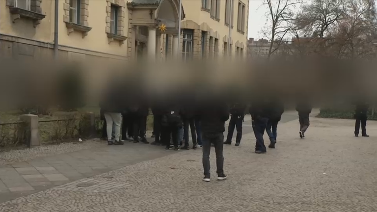 Bild von Schülerinnen und Schülern auf einem Schulhof, alle schwarz gekleidet. Die Identität der Abgebildeten wurde verfremdet.