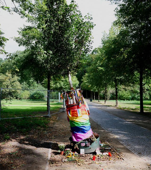 Berlin: Im Tiergarten liegen Blumen, Kerzen und Regenbogenfahnen am beschädigten Gedenkbaum für das Opfer des CSD-Anschlags.
