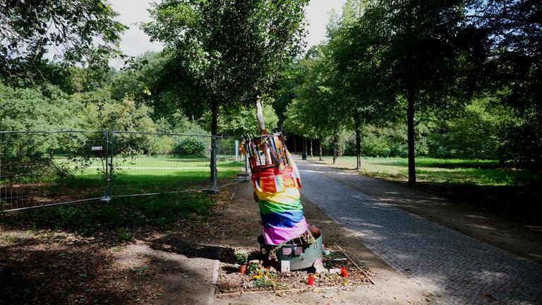 Berlin: Im Tiergarten liegen Blumen, Kerzen und Regenbogenfahnen am beschädigten Gedenkbaum für das Opfer des CSD-Anschlags.
