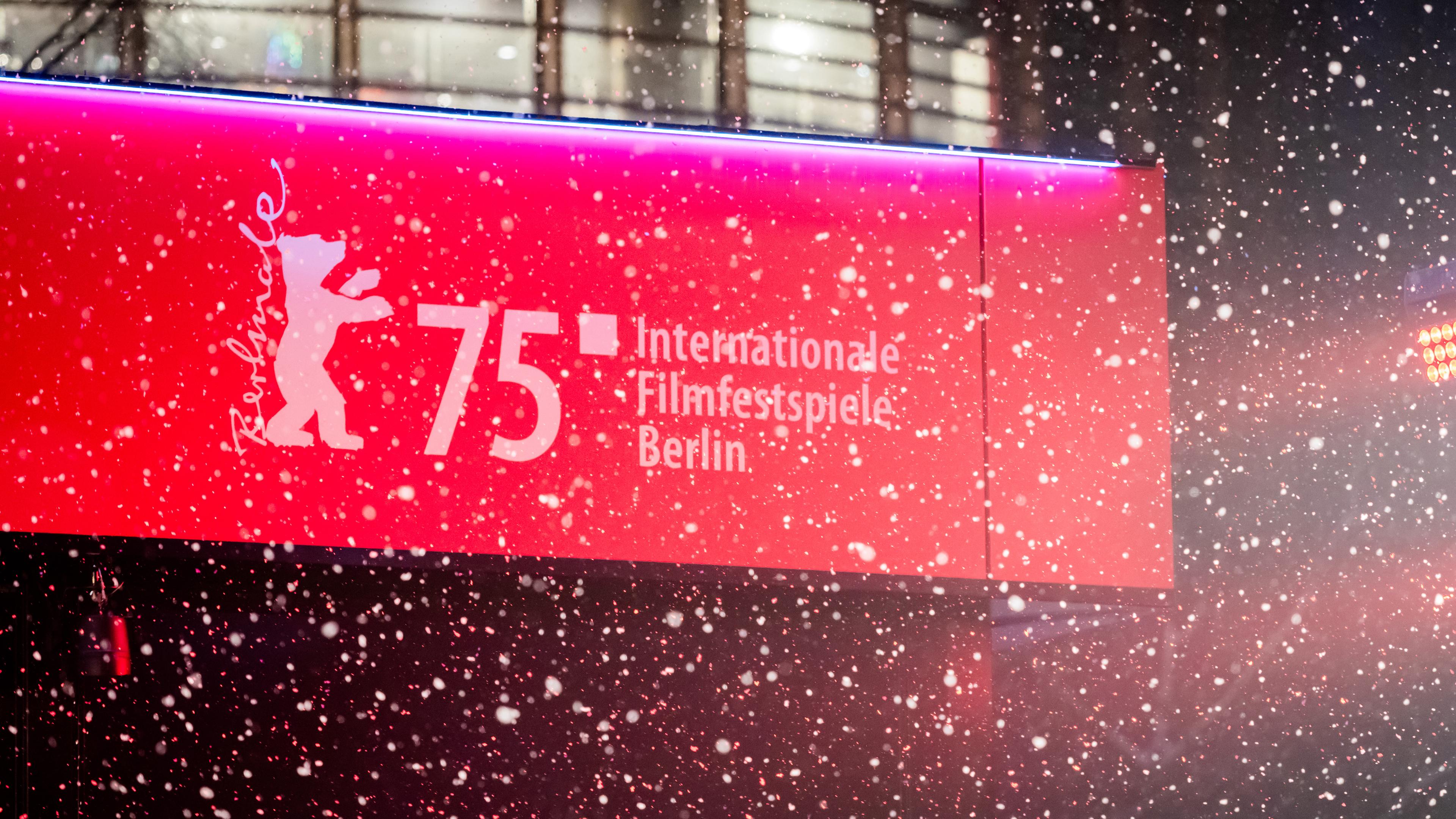 Schnee fällt am Eröffnungsabend der Berlinale auf dem Roten Teppich vor dem Berlinale-Logo.