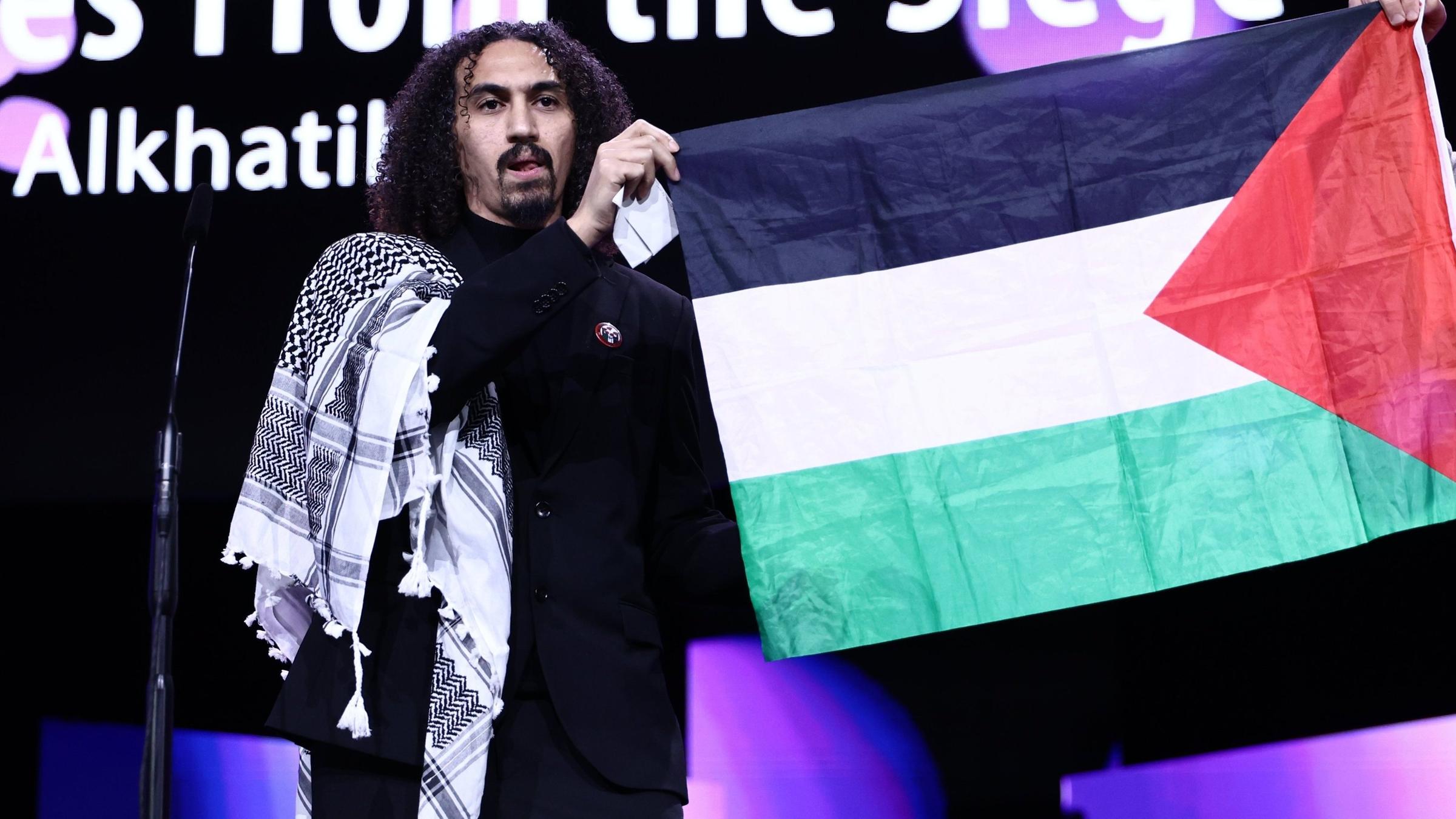Abdallah Alkhatib hält bei der Berlinale-Abschlussgala eine palästinensische Flagge hoch.