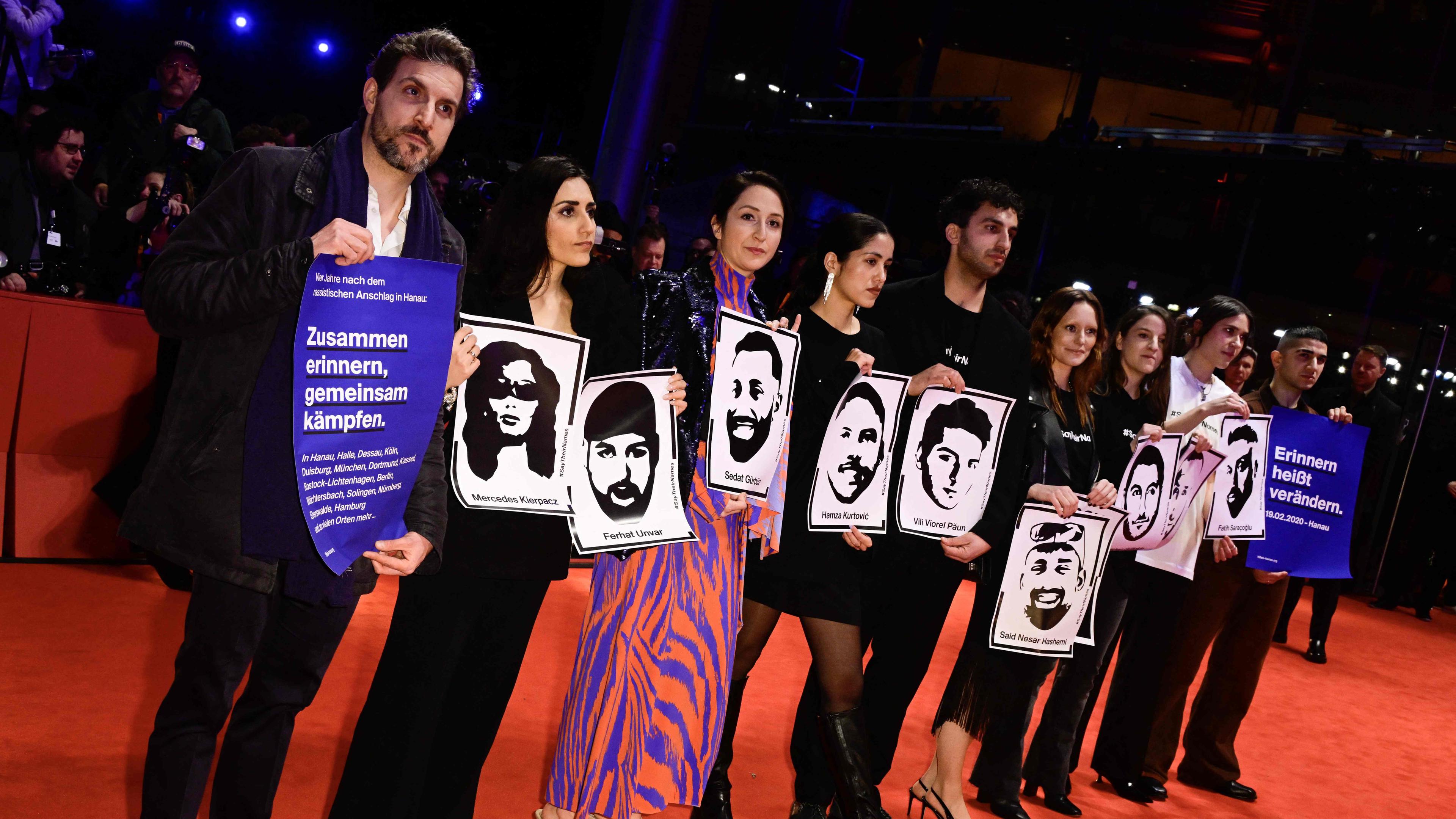 Bei der Eröffnung der 74. Berlinale halten Menschen Plakate hoch, um den Opfern des rassistischen Anschlags in Hanau 2020 zu gedenken.