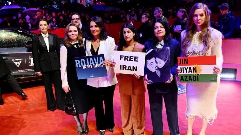 Mehrere Frauen stehen auf dem roten Teppich der Berlinale und halten Schilder, auf denen unter anderem Free Iran steht.