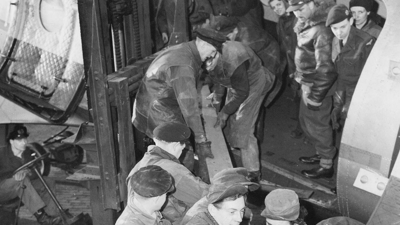 alliierte soldaten entladen ein flugzeug waehrend der berliner luftbruecke