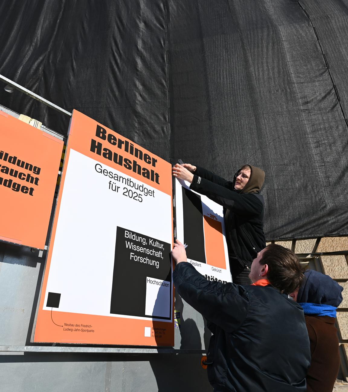 Ein Student hängt Protestplakate gegen Haushaltskürzungen der Unis in Berlin auf.