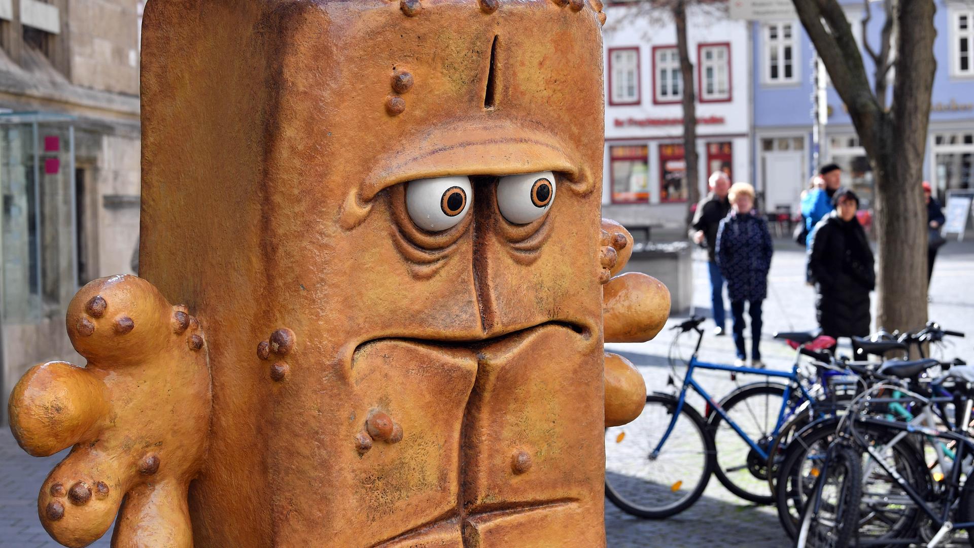 Passanten laufen hinter der Figur "Bernd das Brot" aus dem Kinderfernsehen neben dem Rathaus am Fischmarkt entlang.