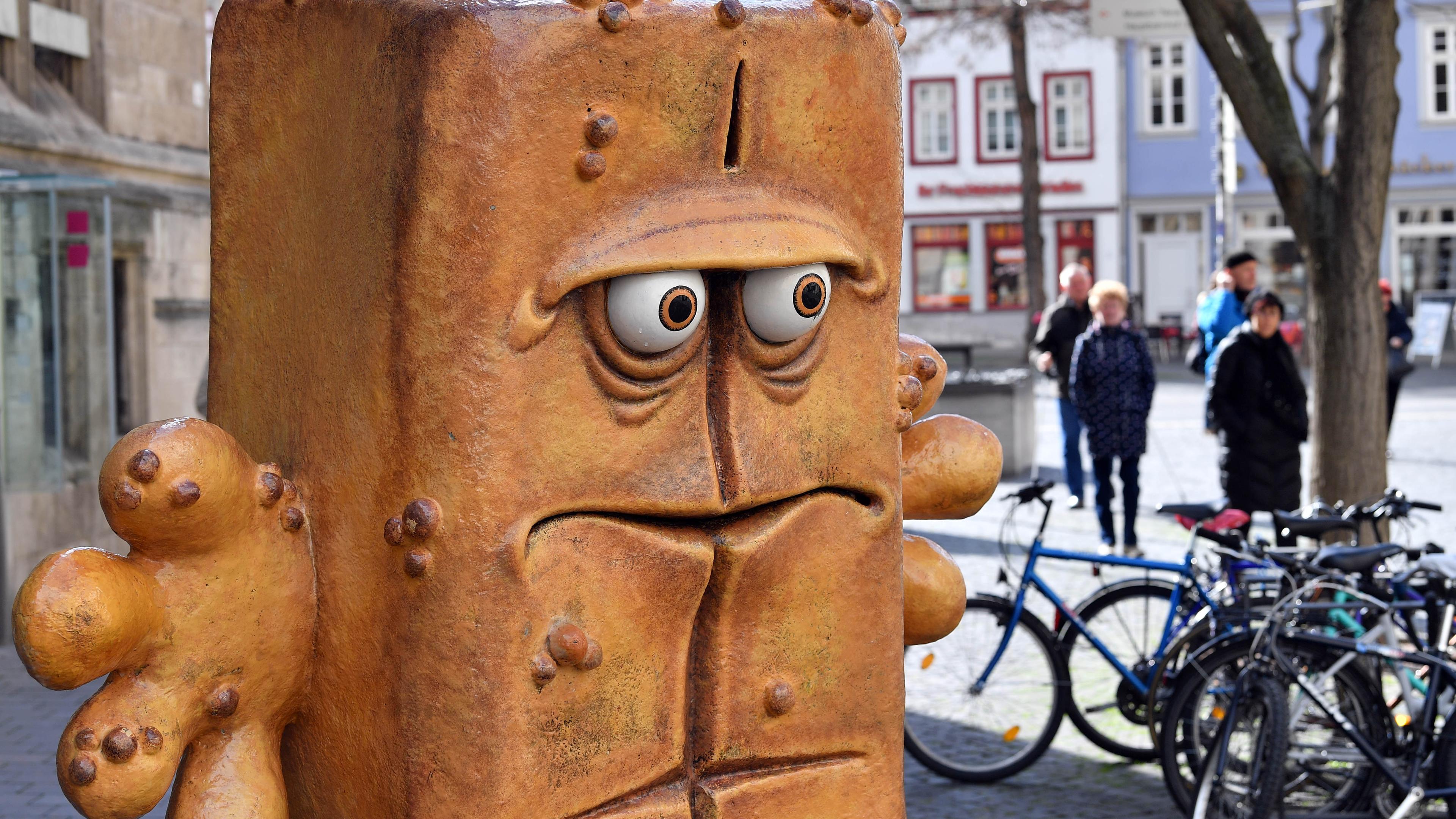 Passanten laufen hinter der Figur "Bernd das Brot" aus dem Kinderfernsehen neben dem Rathaus am Fischmarkt entlang.