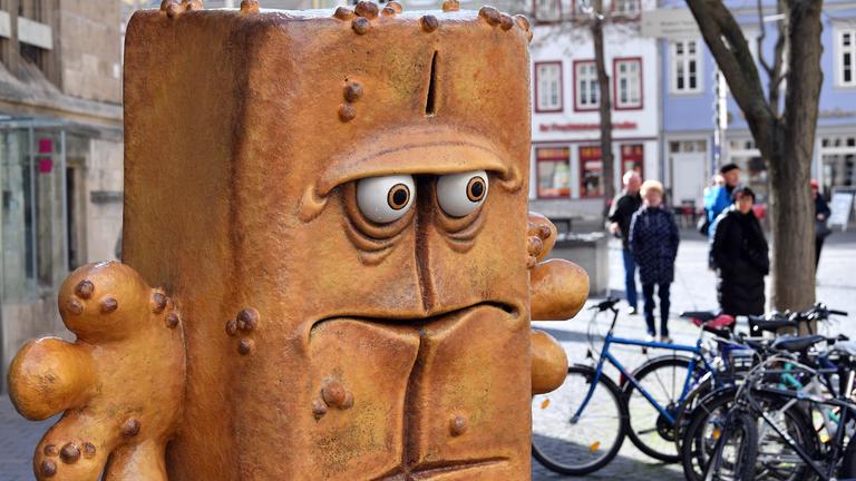 Passanten laufen hinter der Figur "Bernd das Brot" aus dem Kinderfernsehen neben dem Rathaus am Fischmarkt entlang.