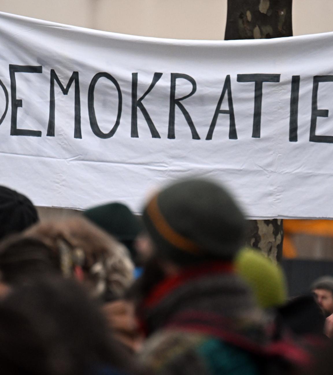 Menschen ziehen während einer Demonstration an einem Banner mit der Aufschrift «Demokratie» vorbei.