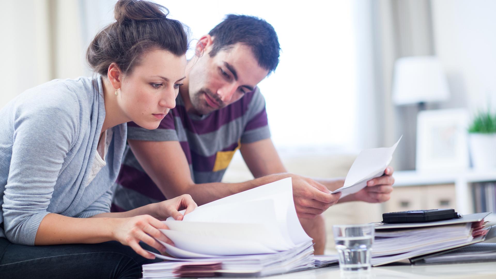 Eine Frau und ein Mann sehen sich Unterlagen und Papiere an.