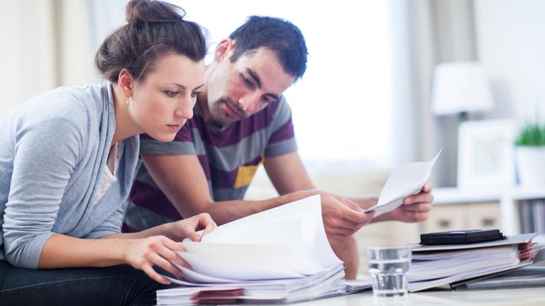 Eine Frau und ein Mann sehen sich Unterlagen und Papiere an.