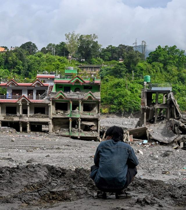 Ein Mann betrachtet am 31.08.2026 im Trishuli Center, im nepalesischen Distrikt Nuwakot, die durch Sturzfluten beschädigten Häuser. 