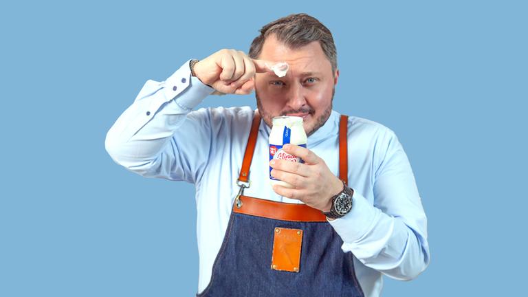 Sebastian Lege hält ein Glas Miracel Whip in einer Hand und präsentiert mit dem Finger der anderen Hand den Inhalt aus dem Glas.