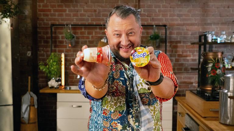 Sebastian Lege steht in seiner Küche und hält zwei Becher Froop in die Kamera.