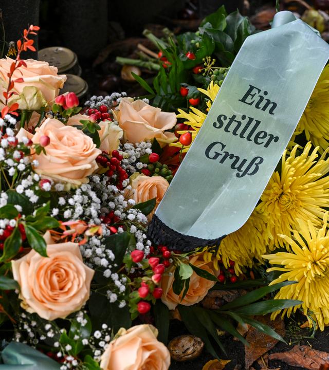 Viele Blumen in einem Strauß mit einem Trauerschleife mit der Aufschrift "Ein stiller Gruß".