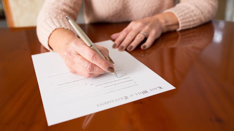 Frau unterschreibt Testament.