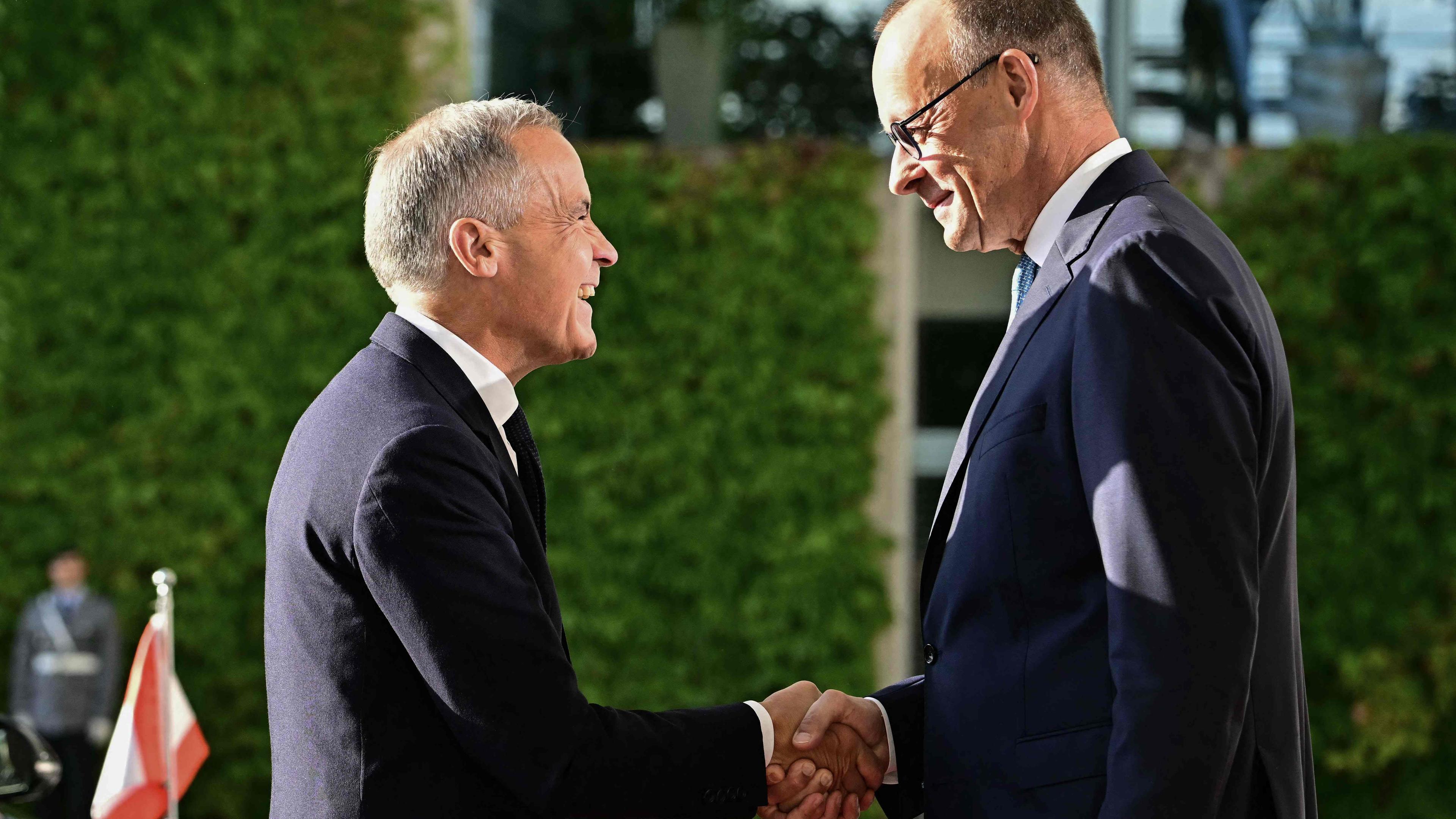 Bundeskanzler Merz und kanadischer Premierminister Mark Carney schütteln sich die Hände in die Berlin.