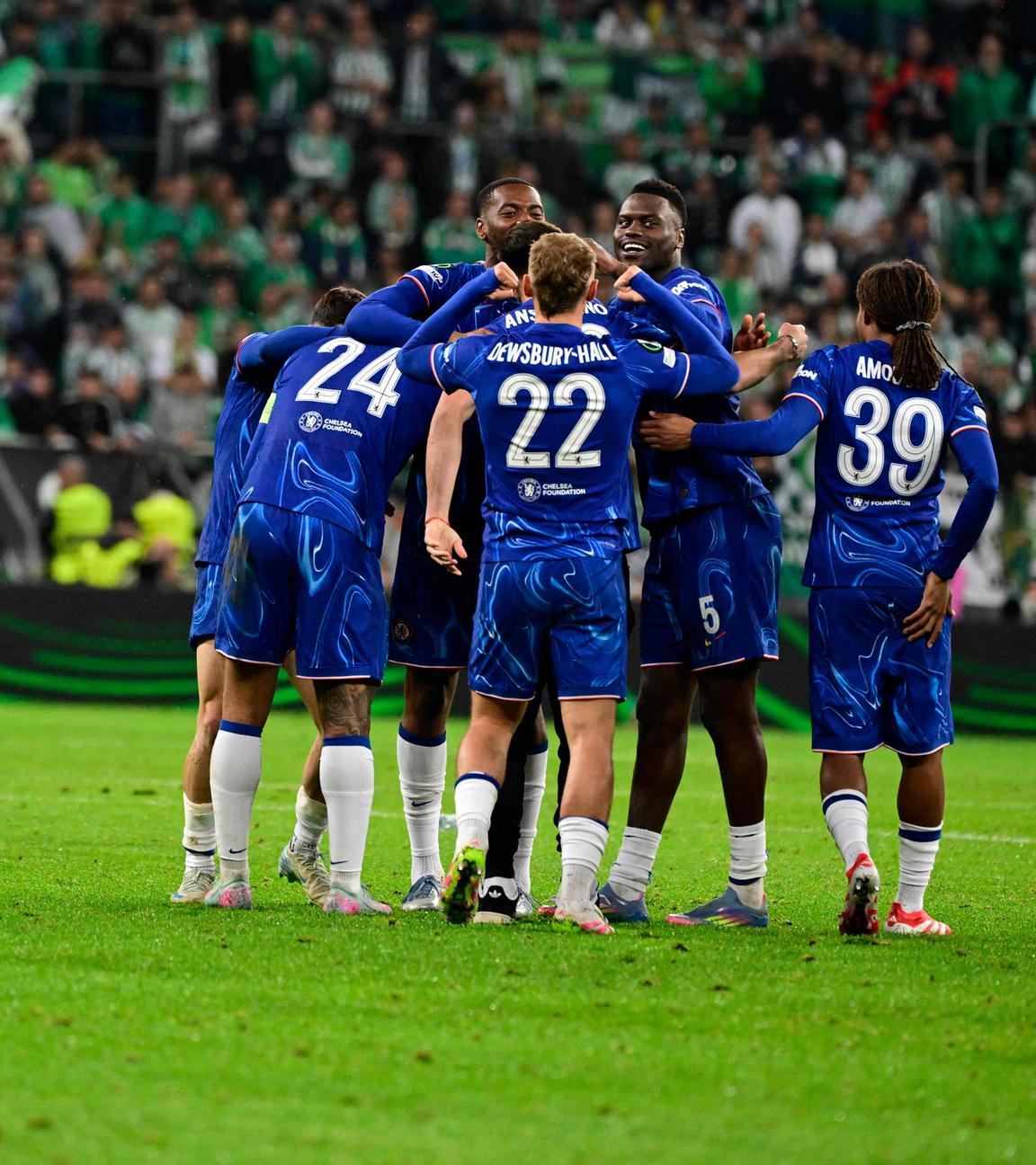 Im Vordergrund kniet ein Betis-Spieler, während im Hintergrund die Spieler des FC Chelsea in einer Jubeltraube feiern.