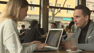 Eine Frau und ein Mann sitzen sich gegenüber in einem Cafe. Die Frau arbeitet am Laptop.