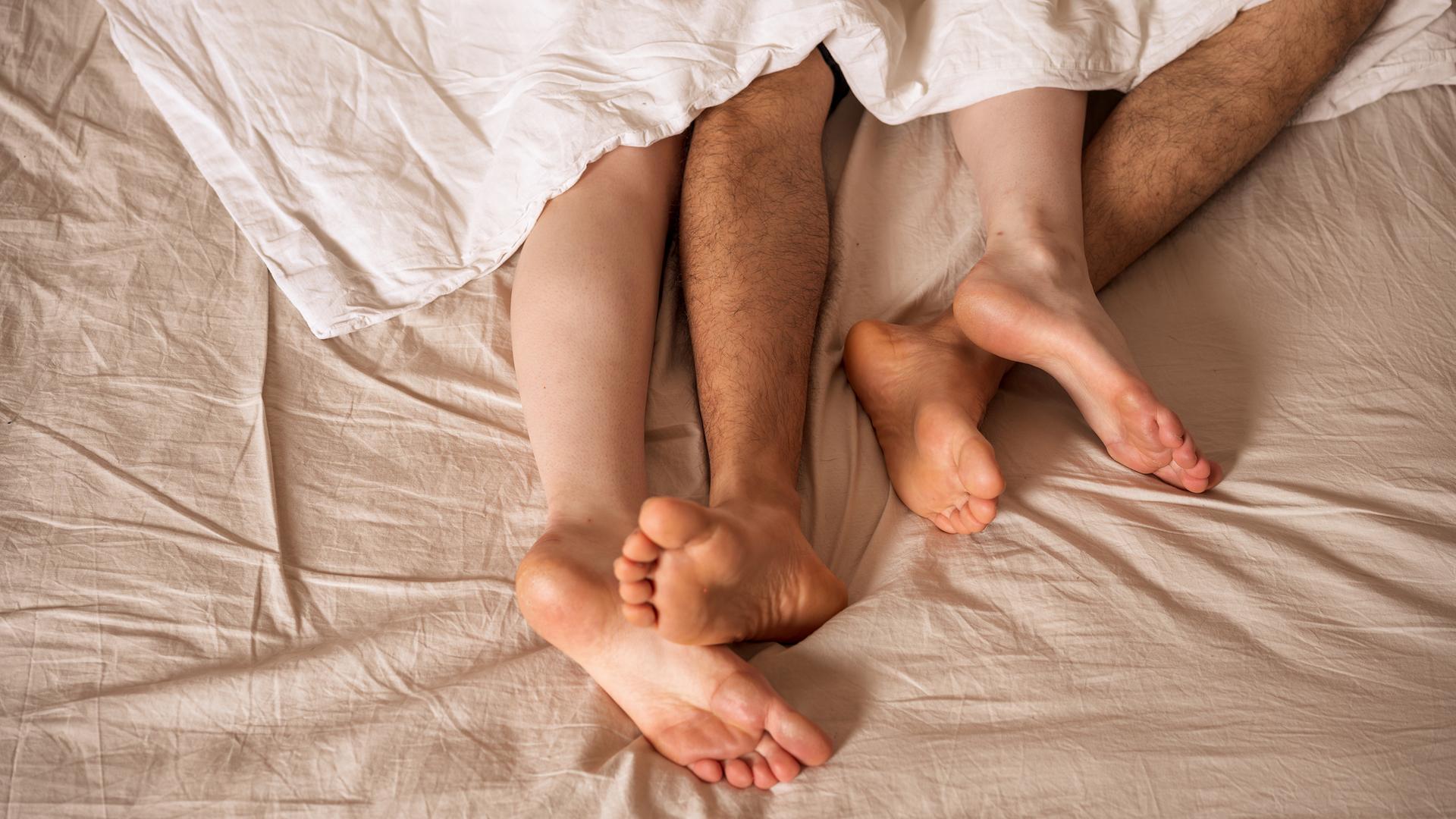 Die Beine von Männern und Frauen ragen unter der Decke hervor.