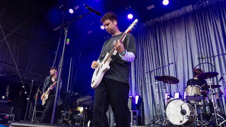 Zwei Musiker stehen auf einer Bühne und spielen Gitarre.