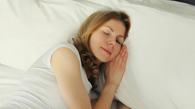 Frau schlafend im Bett liegend auf weißen weichen bequemen Kissen im Schlafzimmer zu Hause