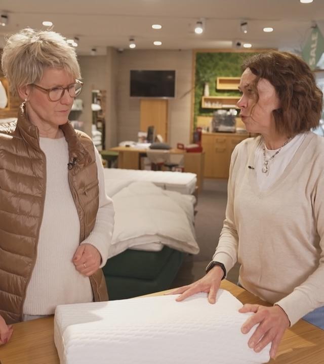 Verkaufsleiterin Katrin Marsch erklärt einer Frau, worauf es bei der Pflege eines Kissens ankommt.